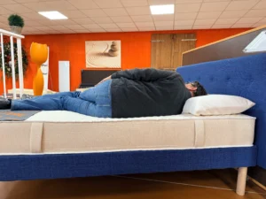 Client testant un matelas sur le côté en magasin OX LITERIE pour vérifier le confort