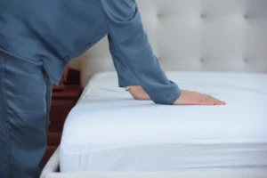 Personne testant la fermeté d'un matelas blanc en magasin pour soulager les douleurs de dos