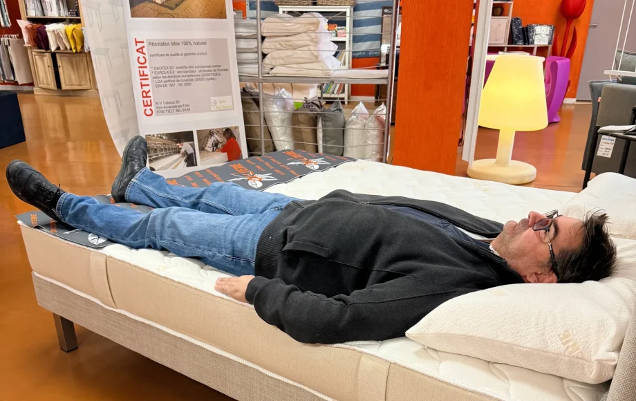 Client allongé sur le dos testant un matelas en magasin OX LITERIE